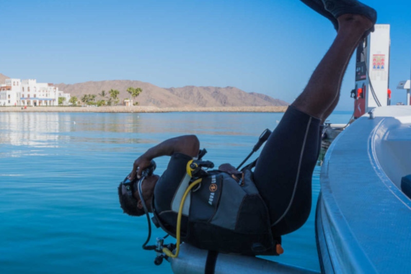 diver at sifah water starting his day with diving session with sifawy hotel behinnd him