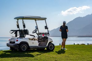 A lady watching the view beside Golf car in Jebel Sifah Oman