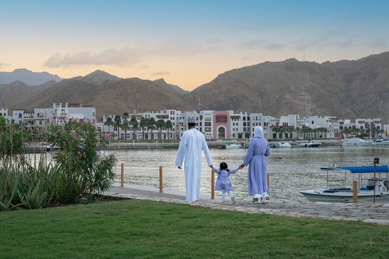 muslim couple carrying child at sifawy hotel with mountains in the background