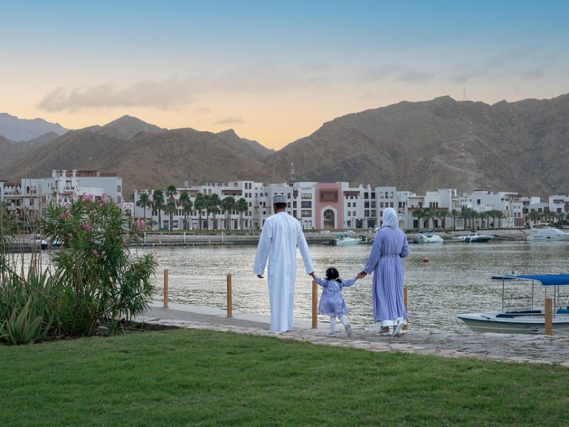muslim couple carrying child at sifawy hotel with mountains in the background